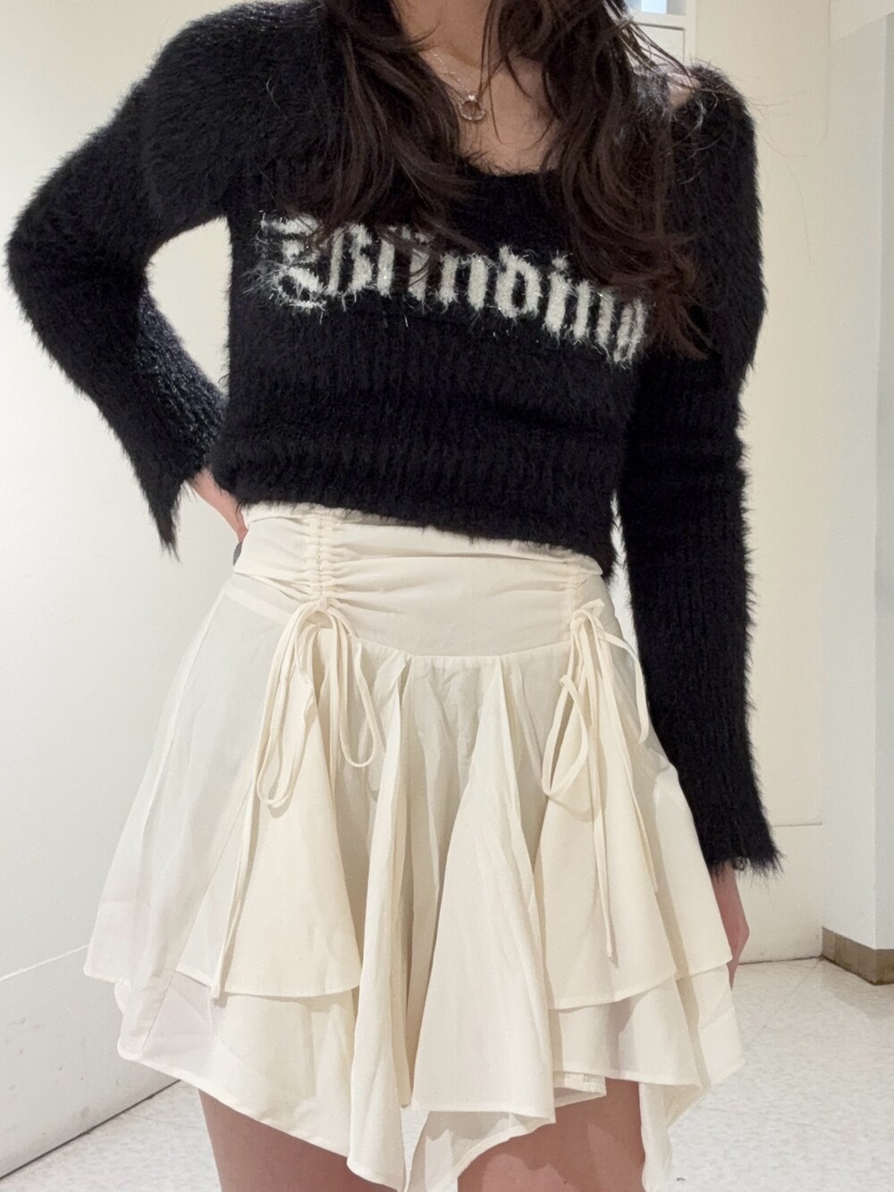 ブラック系のニット/セーター、ホワイト系のスカート、ブラック系のブーツを着用したレディースの冬コーディネートの4枚目の写真