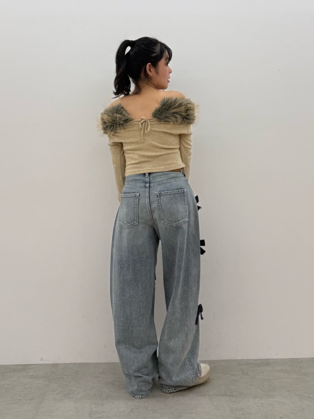 ベージュ系のTシャツ/カットソー、ブルー系のデニムパンツ、ホワイト系のスニーカーを着用したレディースの秋コーディネートの3枚目の写真