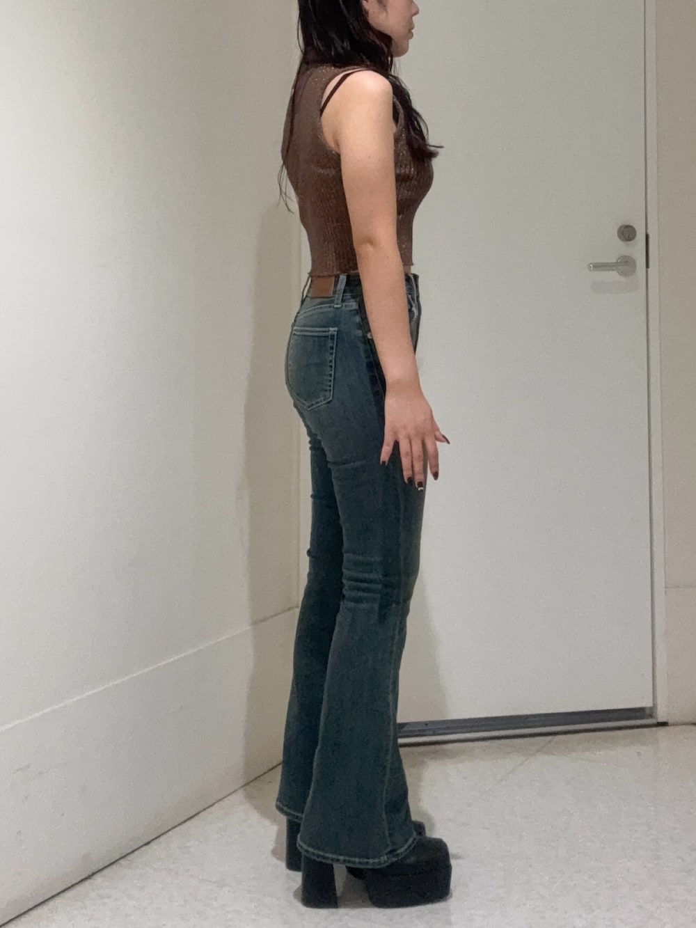 ブラック系のブーツ、ブルー系のデニムパンツ、ブラウン系のタンクトップを着用したレディースの秋コーディネートの2枚目の写真