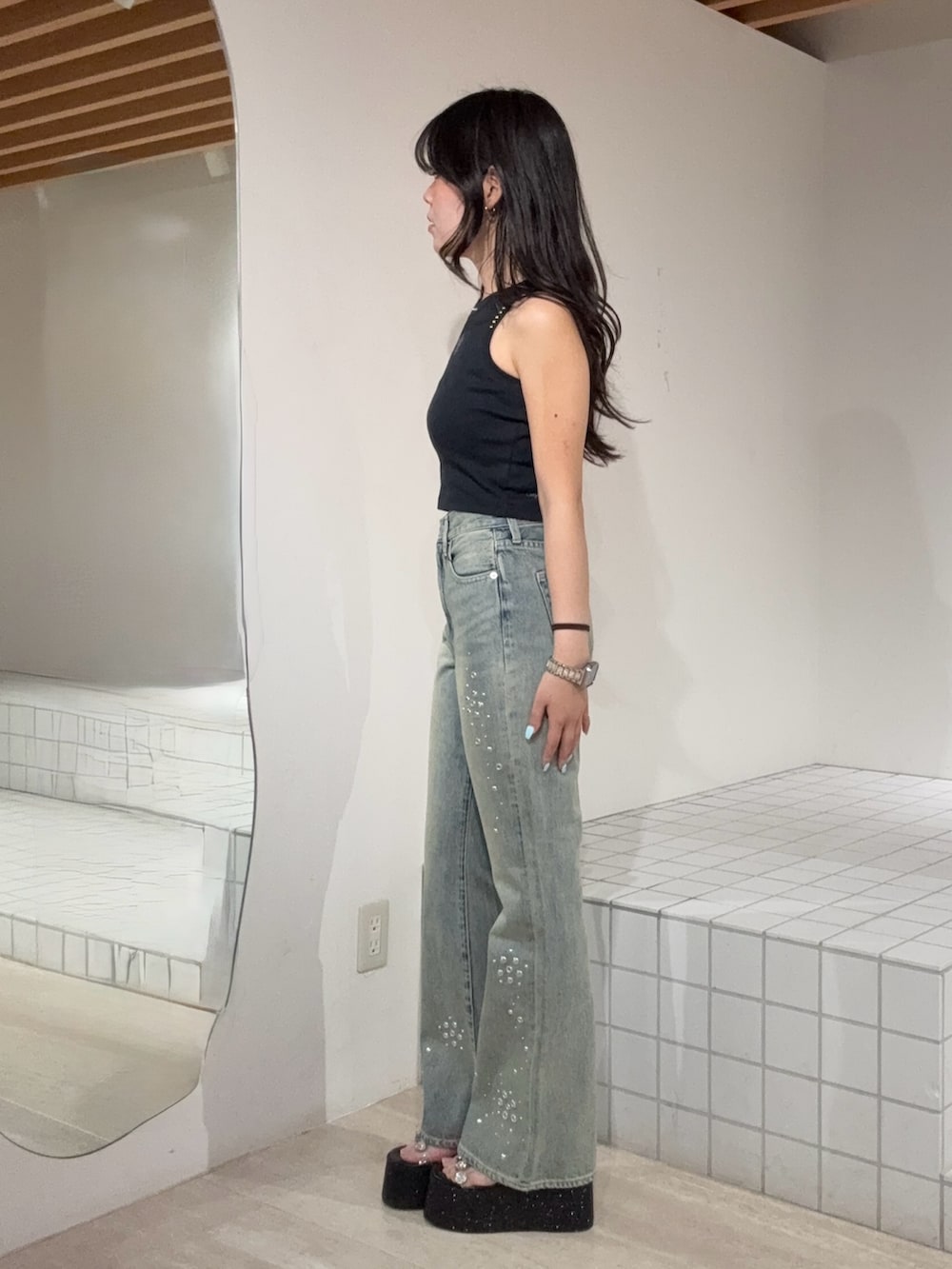 ブラック系のタンクトップ、ブルー系のデニムパンツ、ブラック系のサンダルを着用したレディースの夏コーディネートの2枚目の写真