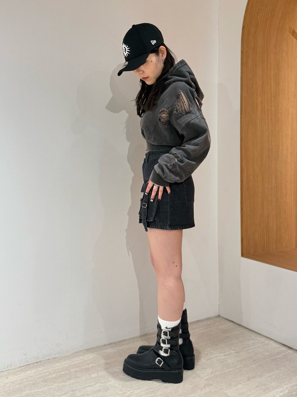 ブラック系のデニムスカート、ブラック系のブーツ、ブラック系のパーカーを着用したレディースの春コーディネートの2枚目の写真