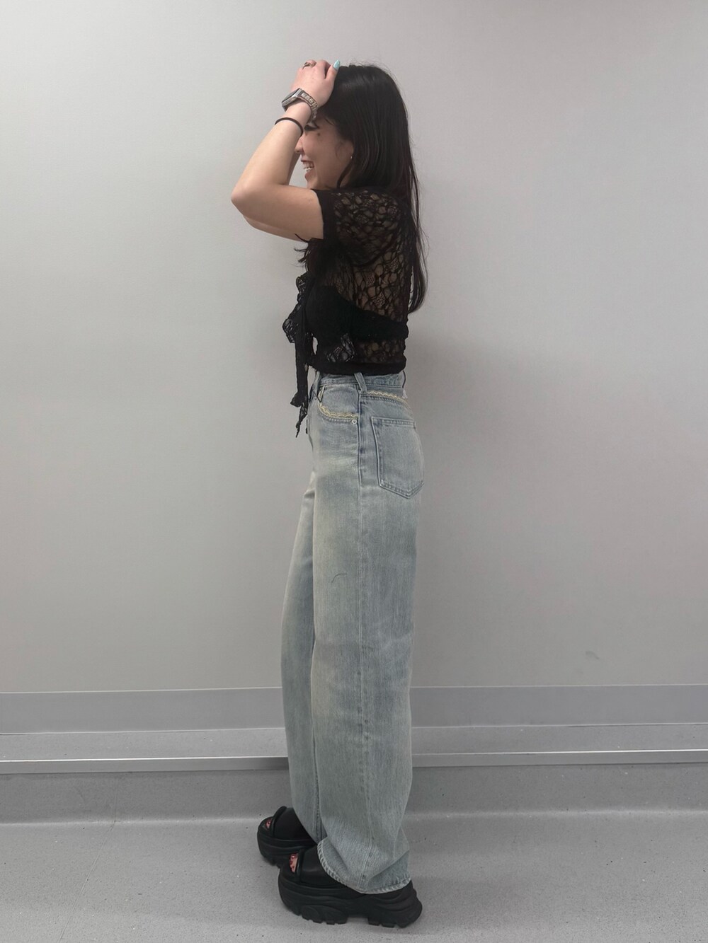 ブルー系のデニムパンツ、ブラウン系のサンダル、ブラック系のTシャツ/カットソーを着用したレディースの春コーディネートの2枚目の写真