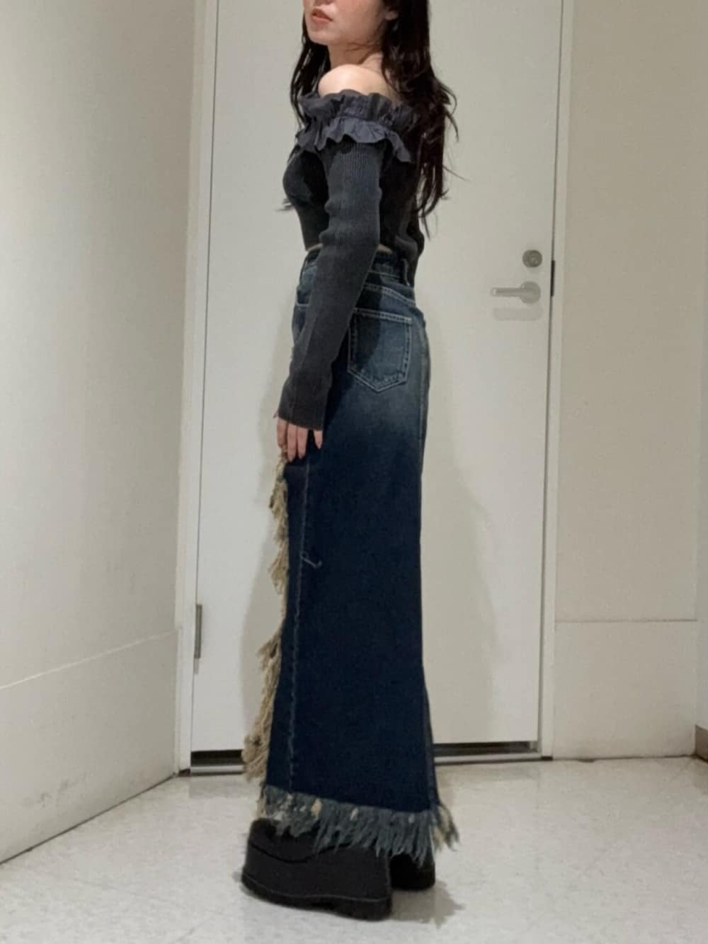 ブラック系のブーツ、ブルー系のデニムスカート、ブラック系のニット/セーターを着用したレディースの冬コーディネートの2枚目の写真