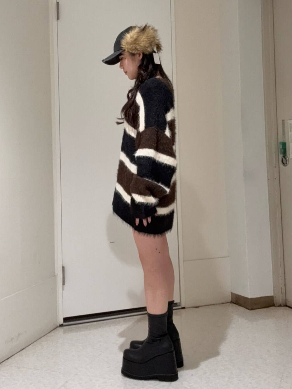 ブラック系のブーツ、ブルー系のデニムパンツ、ブラウン系のニット/セーターを着用したレディースの冬コーディネートの2枚目の写真