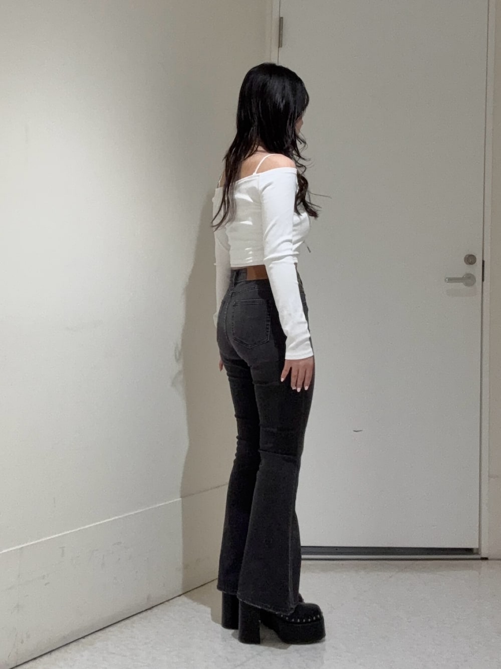 ブラック系のデニムパンツ、ホワイト系のTシャツ/カットソー、ブラック系のサンダルを着用したレディースの春コーディネートの2枚目の写真