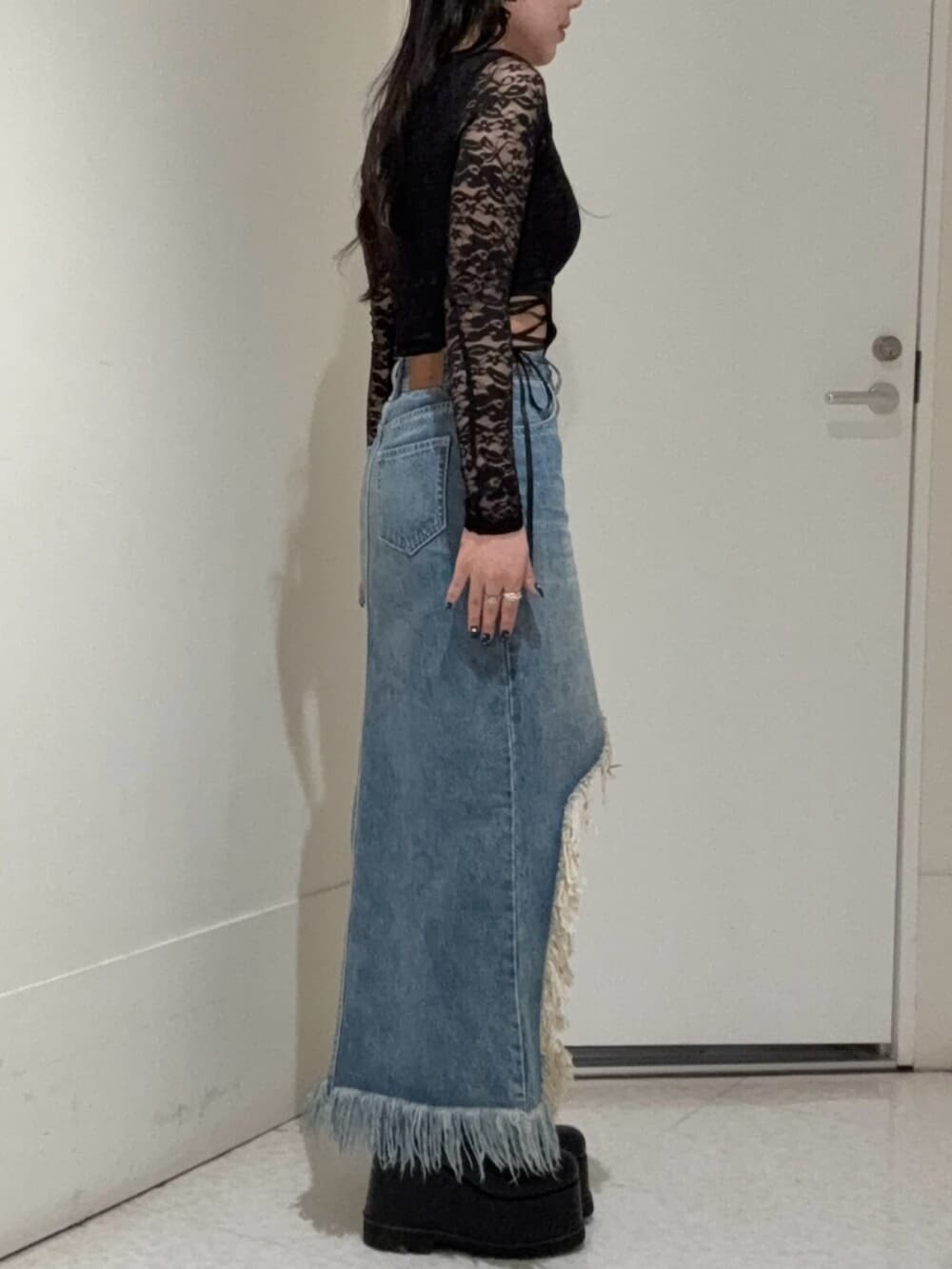 ブラック系のブーツ、ブルー系のデニムスカート、ブラック系のTシャツ/カットソーを着用したレディースの春コーディネートの2枚目の写真