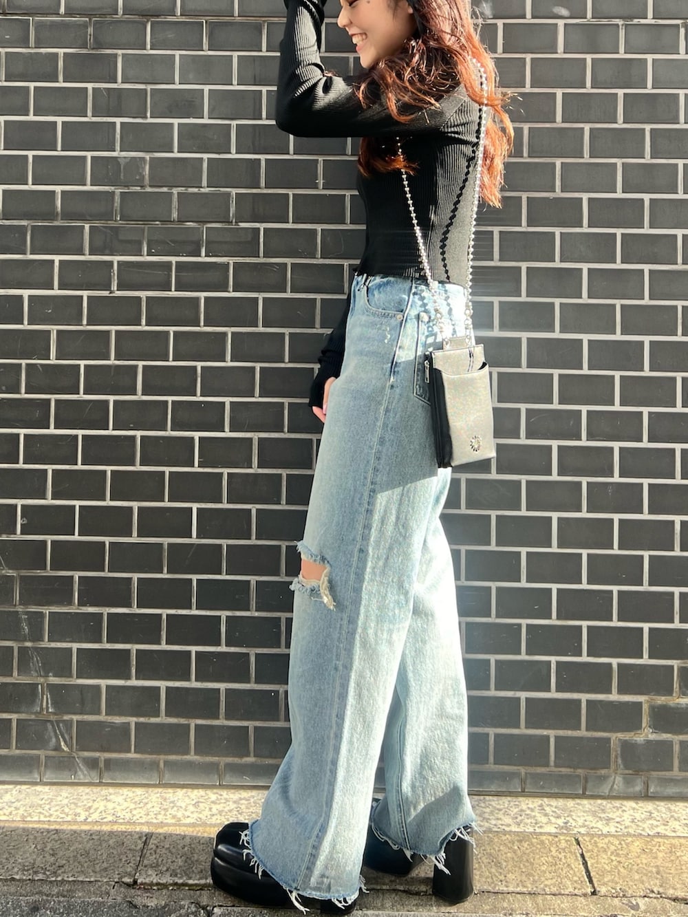 ブルー系のデニムパンツ、ブラック系のニット/セーター、ブラック系のサンダルを着用したレディースの春コーディネートの3枚目の写真