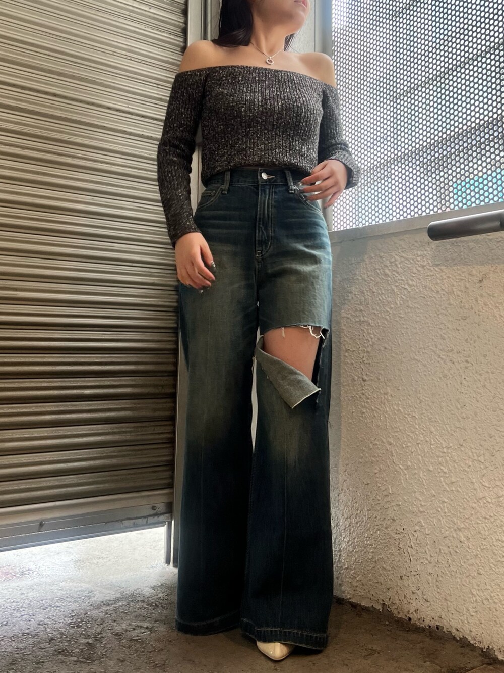 ブルー系のデニムパンツ、ホワイト系のブーツ、ブラック系のニット/セーターを着用したレディースの春コーディネートの2枚目の写真