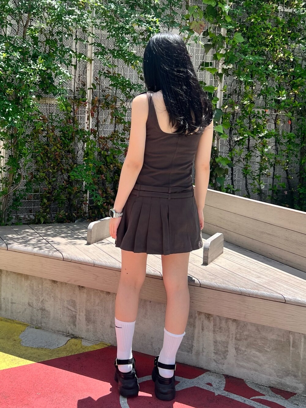 グレー系のジャンパースカート、ブラック系のサンダルを着用したレディースの春コーディネートの4枚目の写真