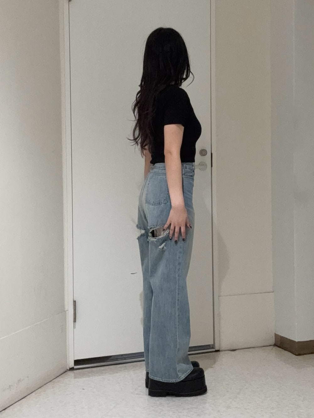 ブラック系のニット/セーター、ブルー系のデニムパンツ、ブラック系のブーツを着用したレディースの春コーディネートの2枚目の写真