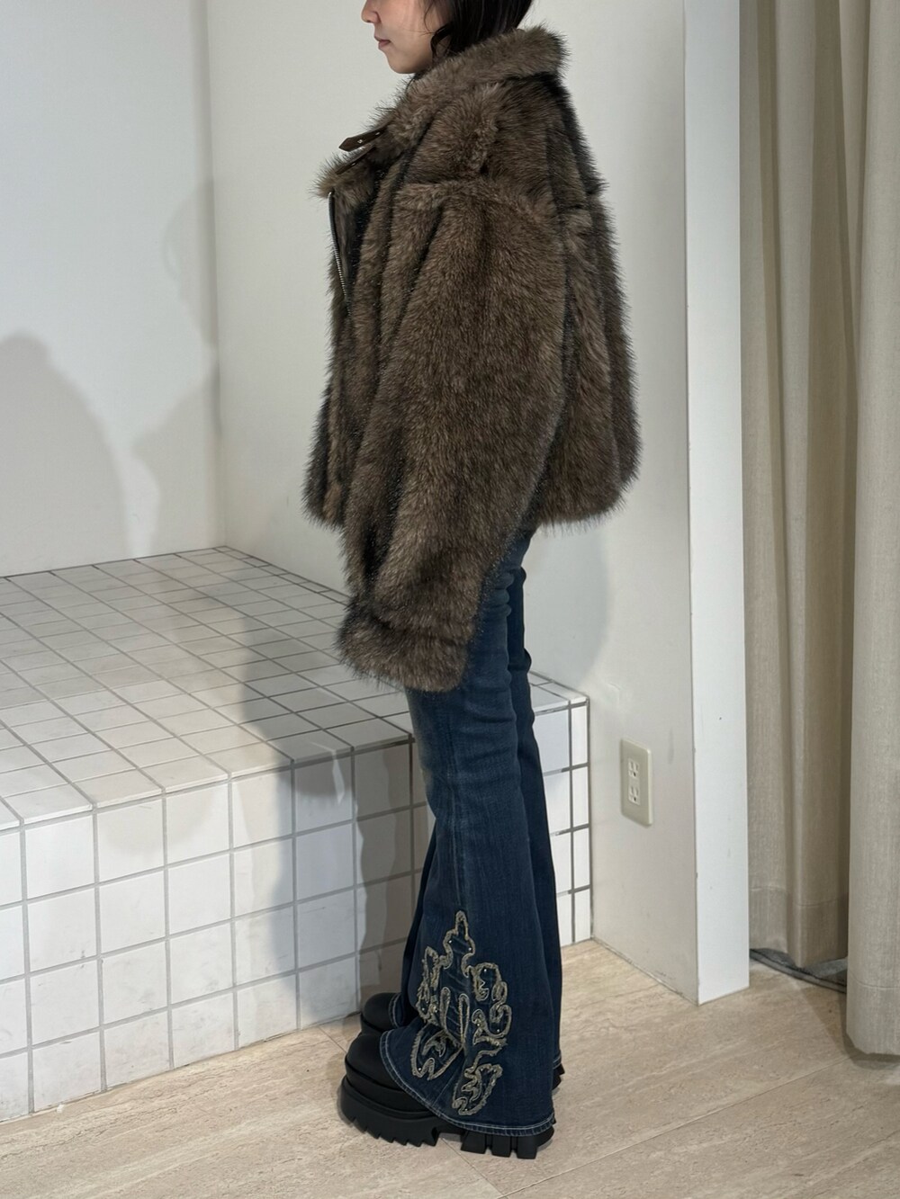 ブラウン系のブルゾン、ブルー系のデニムパンツ、ブラック系のブーツを着用したレディースの秋コーディネートの2枚目の写真