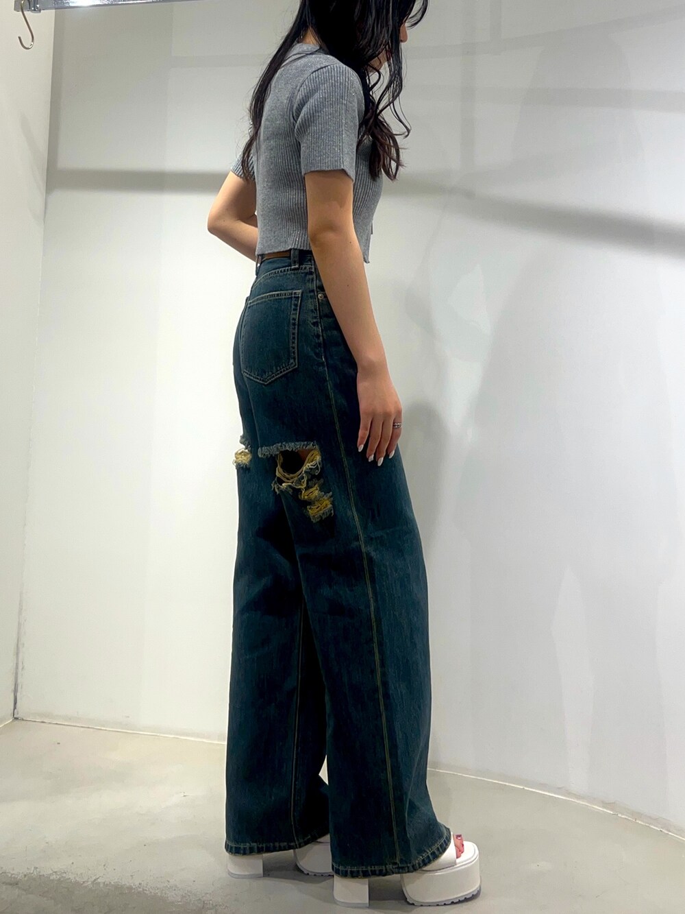 ブルー系のデニムパンツ、ホワイト系のサンダル、グレー系のニット/セーターを着用したレディースの夏コーディネートの2枚目の写真