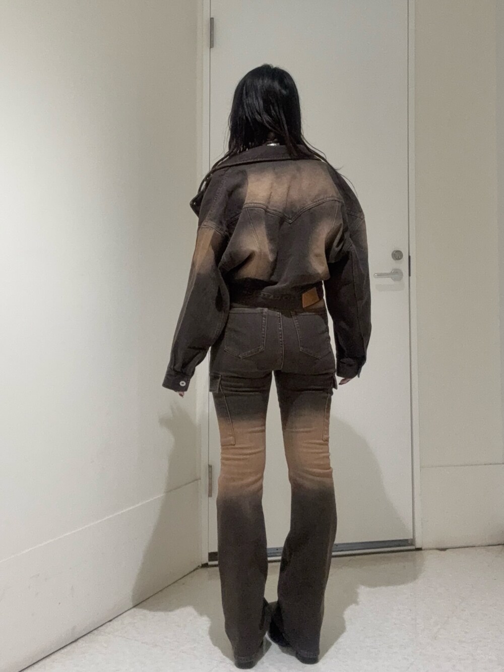 ブラック系のブーツ、ブラウン系のタンクトップ、ブラウン系のデニムジャケットを着用したレディースの秋コーディネートの3枚目の写真