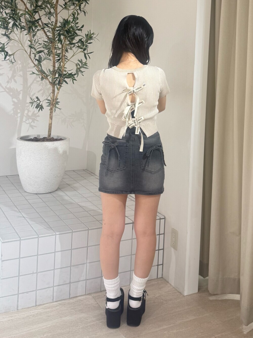 ブラック系のデニムスカート、ブラック系のサンダル、ベージュ系のニット/セーターを着用したレディースの夏コーディネートの3枚目の写真