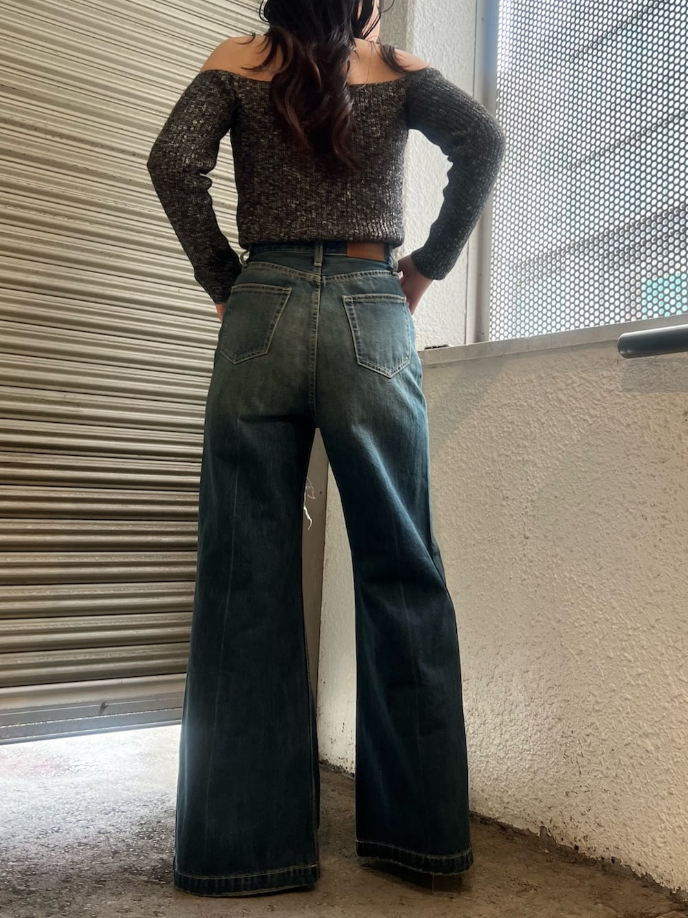 ブルー系のデニムパンツ、ホワイト系のブーツ、ブラック系のニット/セーターを着用したレディースの春コーディネートの4枚目の写真