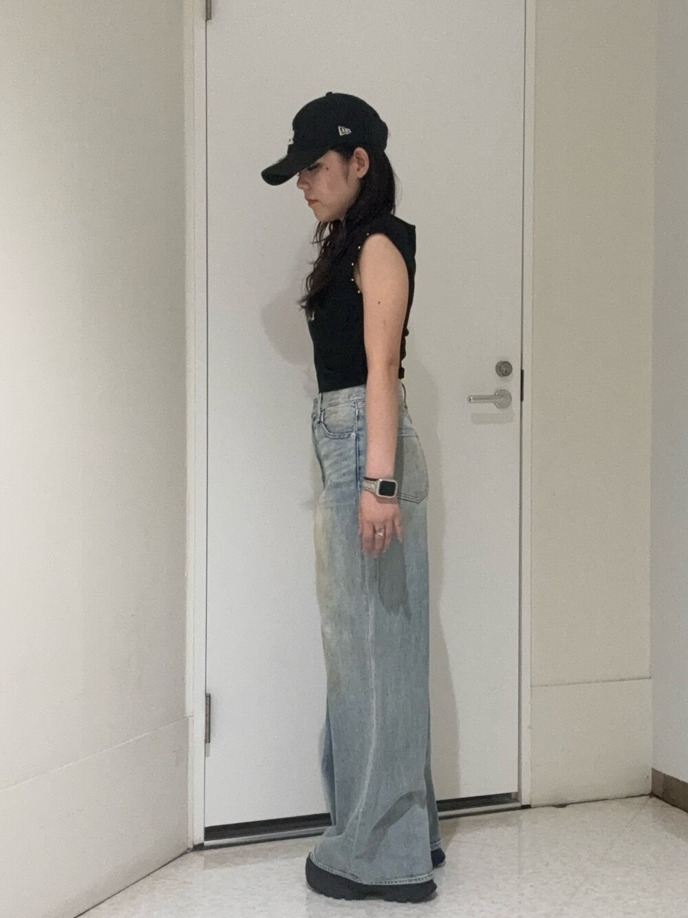 ブラック系のタンクトップ、ブラウン系のサンダル、ブルー系のデニムパンツを着用したレディースの夏コーディネートの2枚目の写真