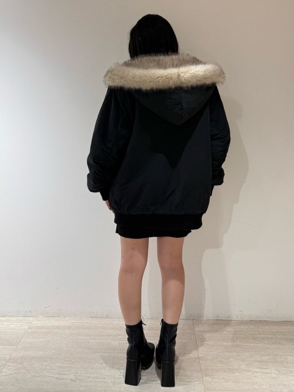 ブラック系のブルゾン、ブラック系のブーツ、ブラック系のワンピースを着用したレディースの冬コーディネートの3枚目の写真