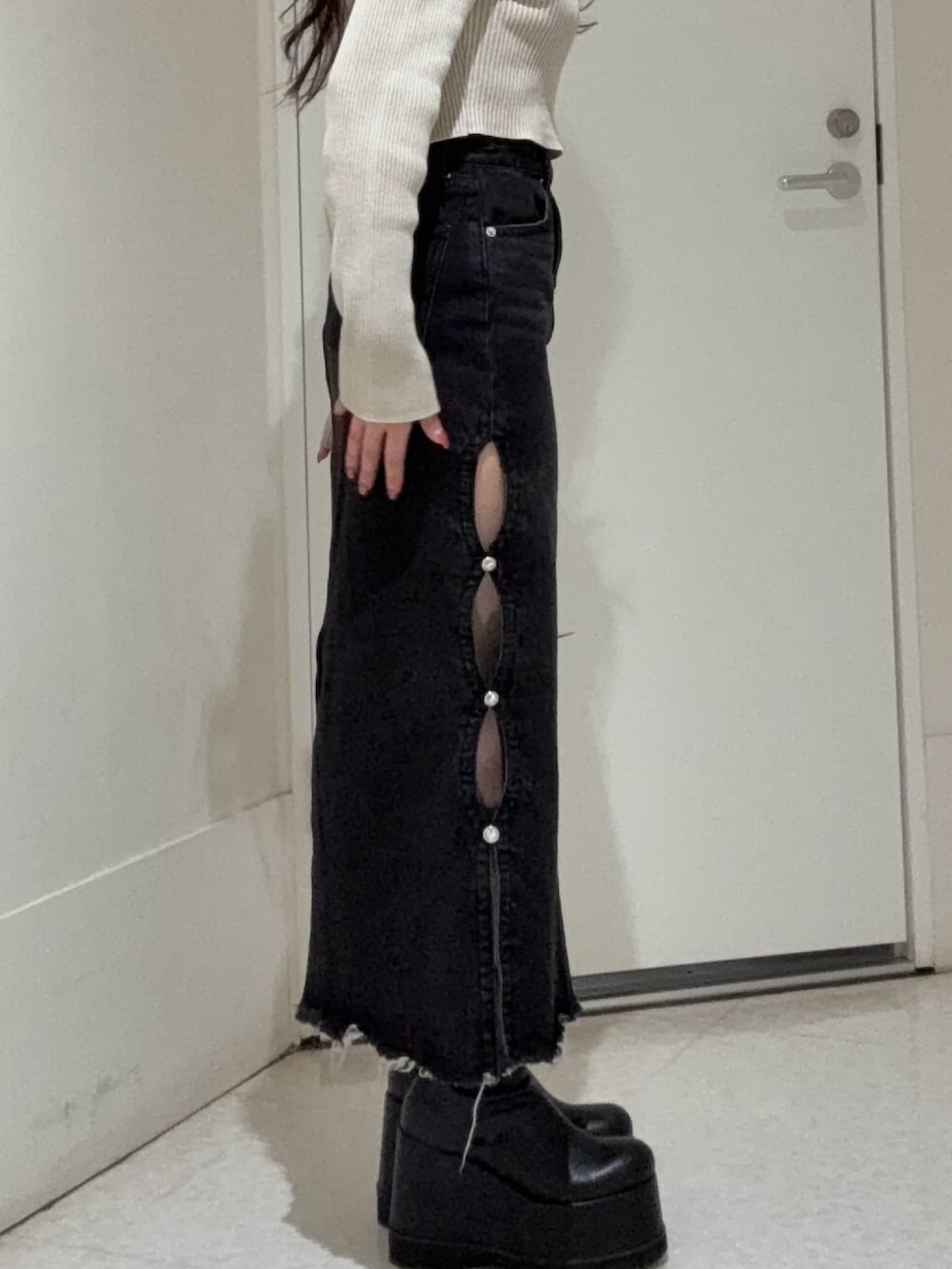 ベージュ系のニット/セーター、ブラック系のデニムスカート、ブラック系のブーツを着用したレディースの春コーディネートの4枚目の写真