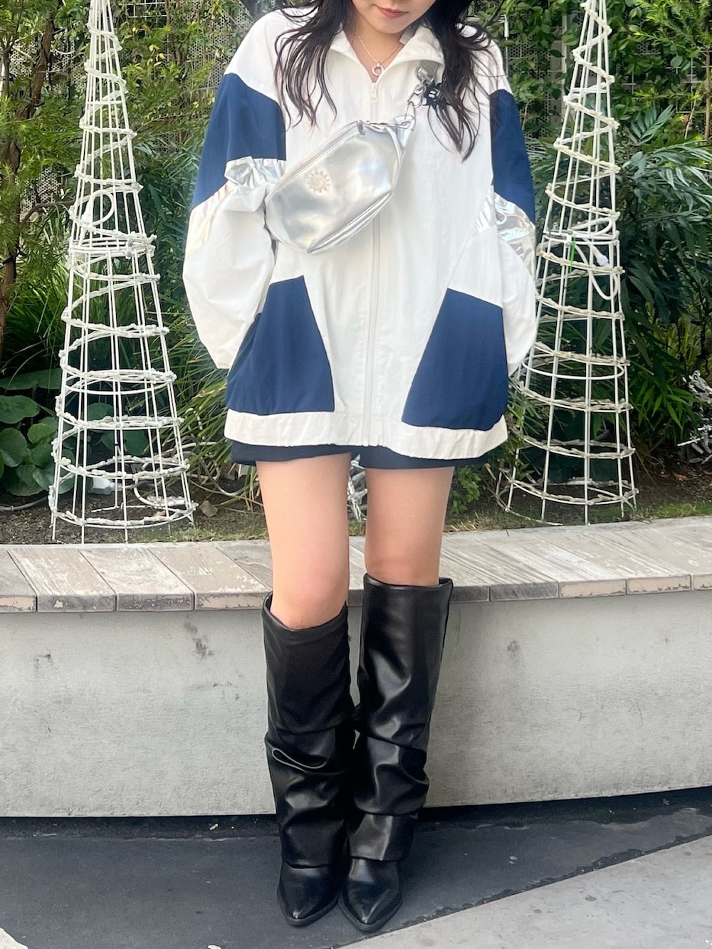 ホワイト系のナイロンジャケット、シルバー系のボディバッグ/ウエストポーチ、ブラック系のブーツを着用したレディースの冬コーディネートの2枚目の写真