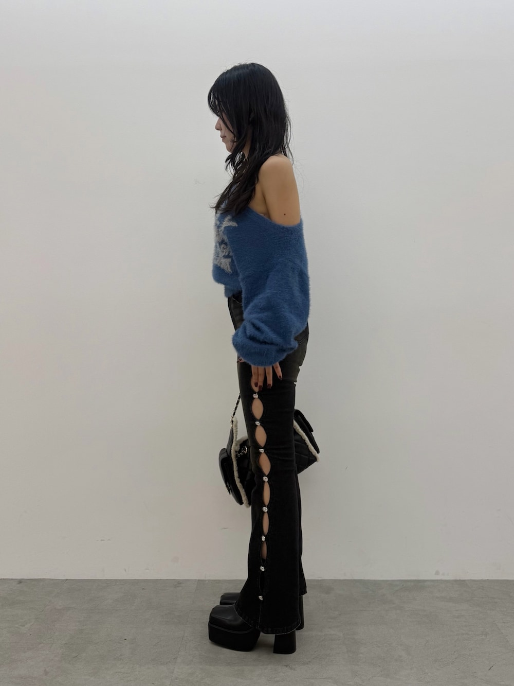 ブルー系のニット/セーター、ブラック系のデニムパンツ、ブラック系のブーツを着用したレディースの秋コーディネートの2枚目の写真