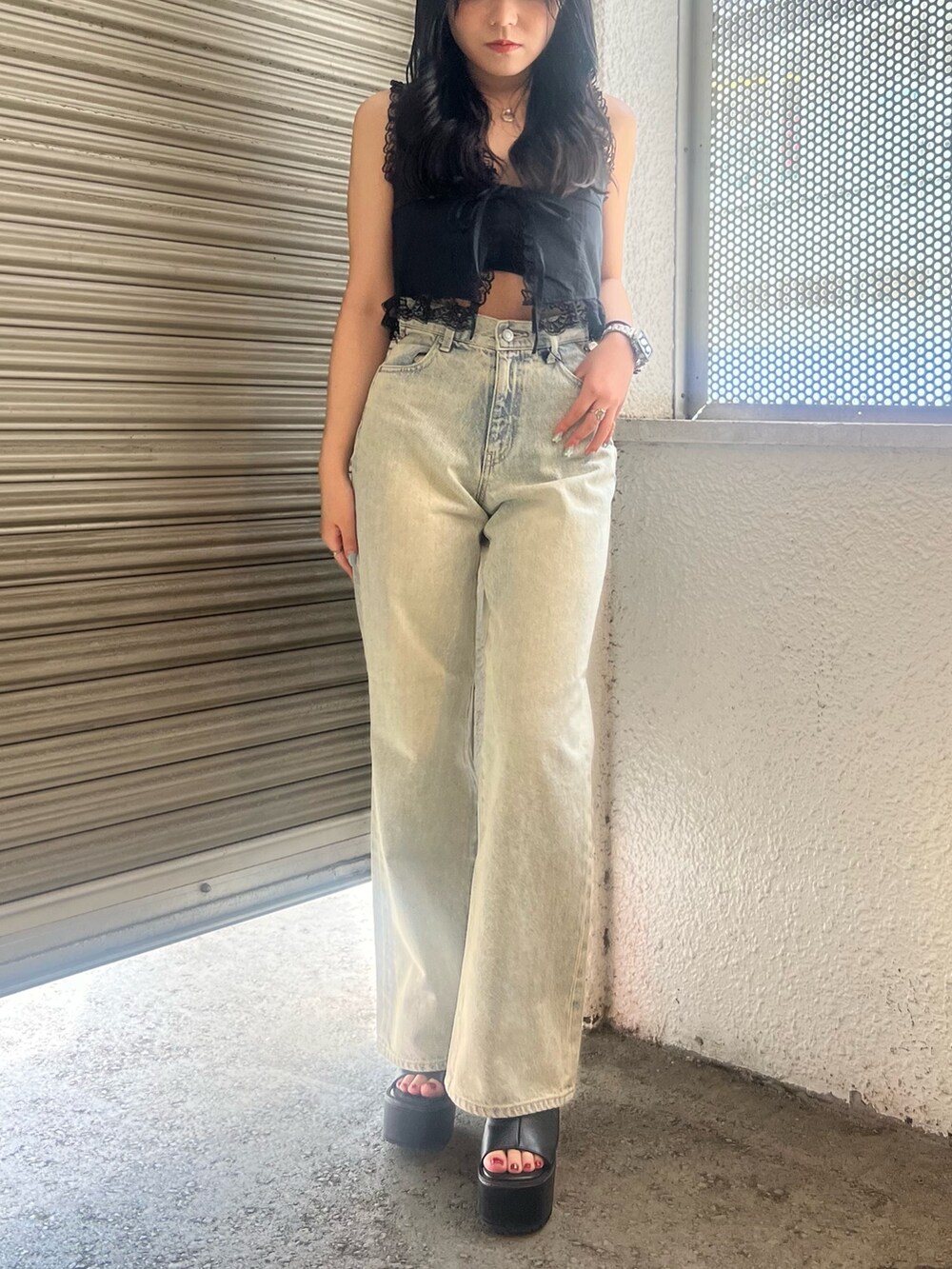 ブルー系のデニムパンツ、ブラック系のサンダルを着用したレディースの夏コーディネートの2枚目の写真
