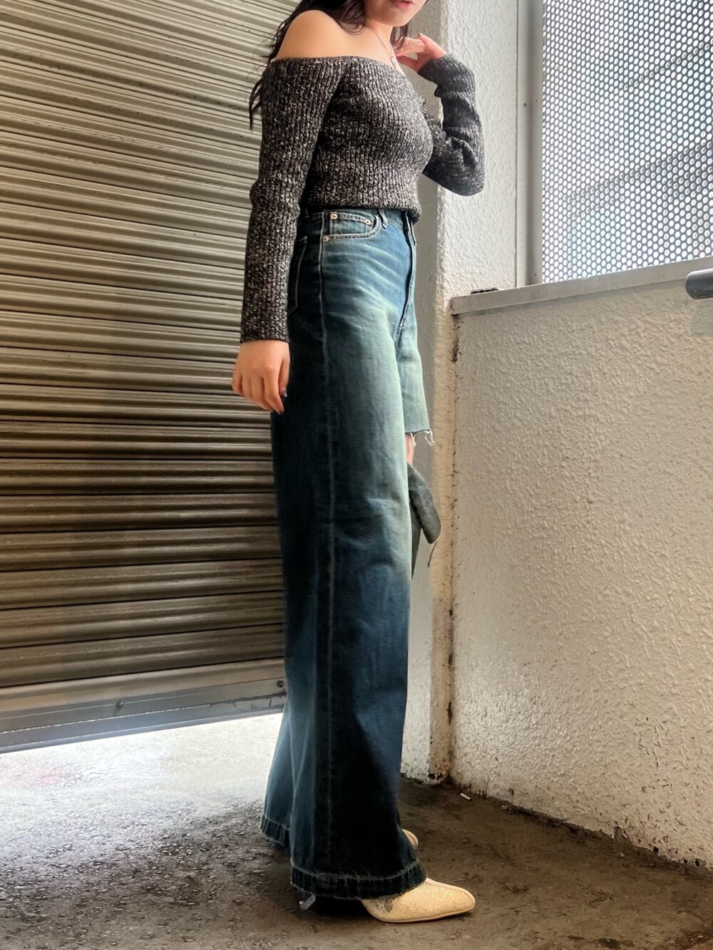 ブルー系のデニムパンツ、ホワイト系のブーツ、ブラック系のニット/セーターを着用したレディースの春コーディネートの3枚目の写真