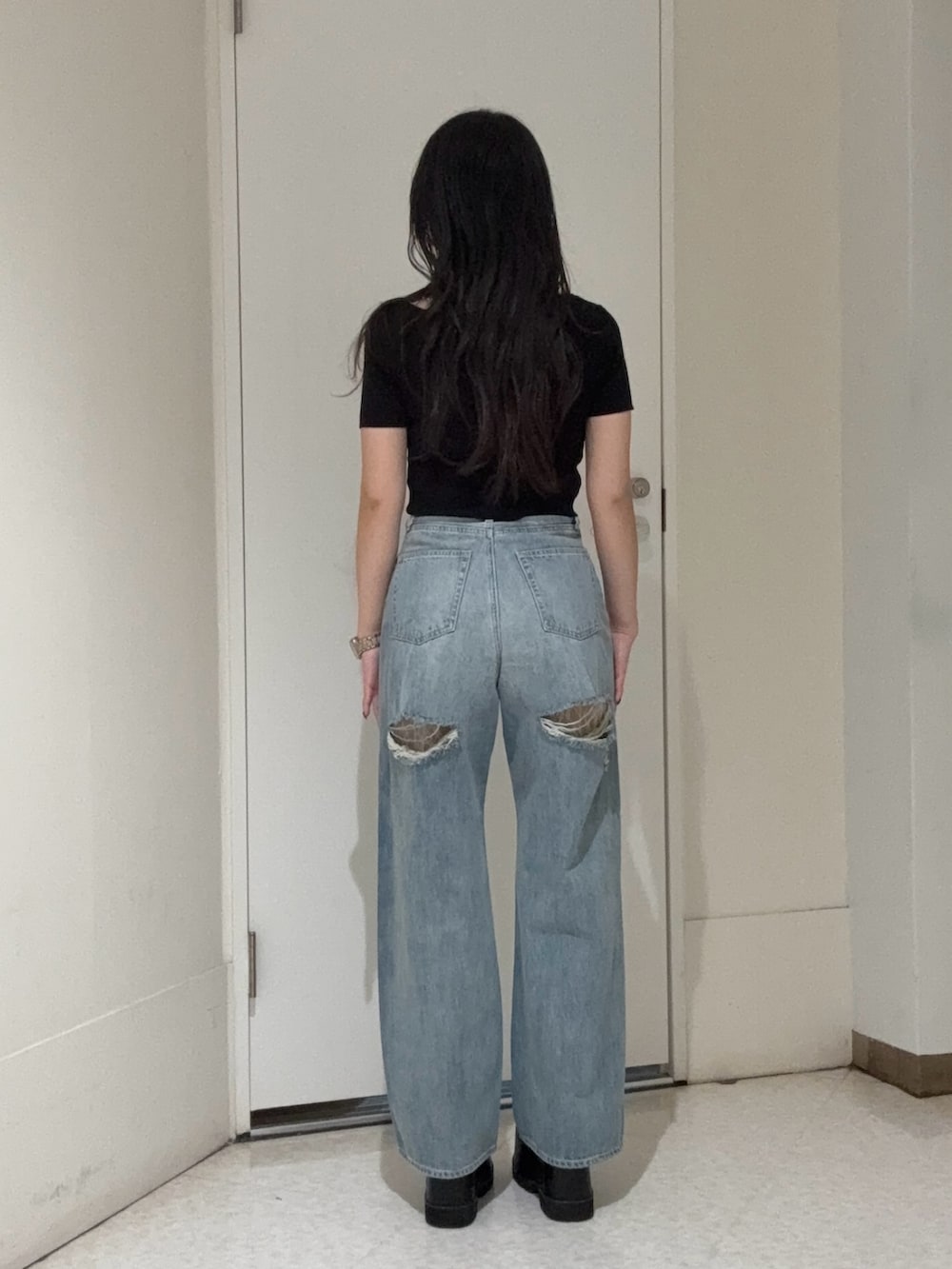 ブラック系のニット/セーター、ブルー系のデニムパンツ、ブラック系のブーツを着用したレディースの春コーディネートの3枚目の写真