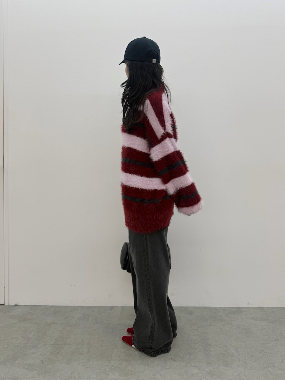 レッド系のニット/セーター、ブラック系のデニムパンツ、レッド系のスニーカーを着用したレディースの秋コーディネートの2枚目の写真