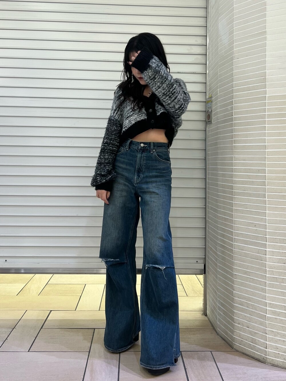 ブルー系のデニムパンツ、ブラック系のカーディガン/ボレロ、ブラック系のブーツを着用したレディースの冬コーディネートの2枚目の写真