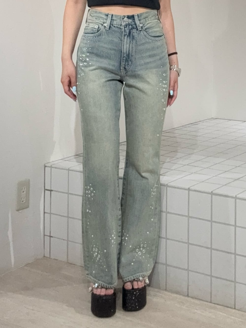 ブラック系のタンクトップ、ブルー系のデニムパンツ、ブラック系のサンダルを着用したレディースの夏コーディネートの5枚目の写真