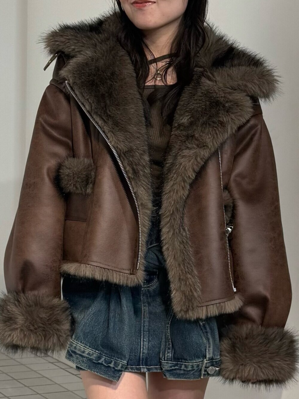 ブルー系のスカート、ブラウン系のブルゾン、ブラック系のブーツを着用したレディースの秋コーディネートの4枚目の写真