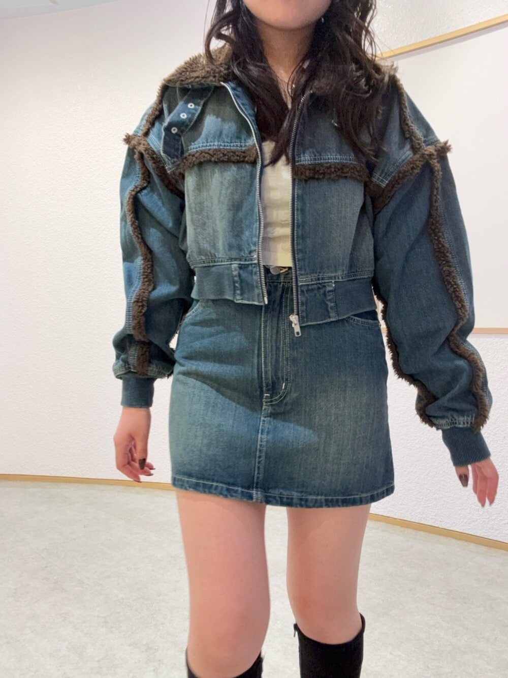 ブラック系のブーツ、ブルー系のブルゾン、ブルー系のデニムスカートを着用したレディースの秋コーディネートの4枚目の写真