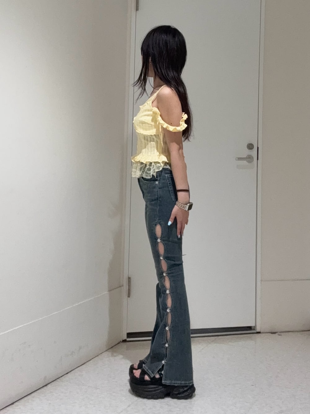 イエロー系のキャミソール、ブルー系のデニムパンツ、ブラック系のサンダルを着用したレディースの春コーディネートの2枚目の写真