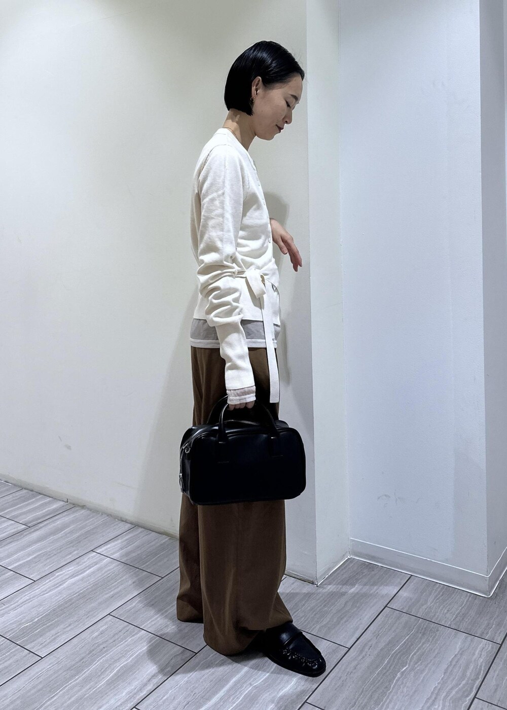 ブラック系のショルダーバッグ、ブラウン系のその他パンツ、ホワイト系のカーディガン/ボレロを着用したレディースの秋コーディネートの5枚目の写真