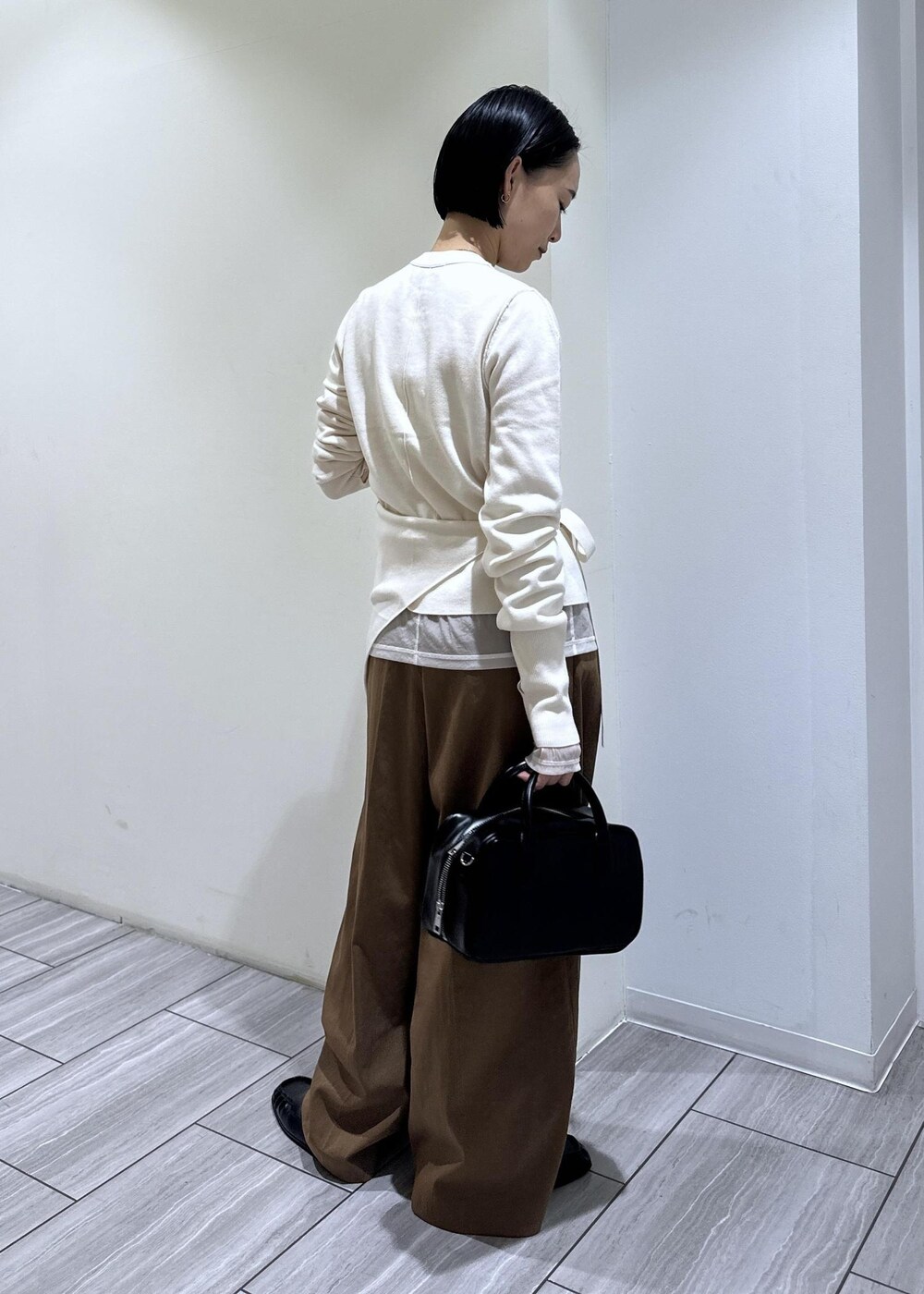 ブラック系のショルダーバッグ、ブラウン系のその他パンツ、ホワイト系のカーディガン/ボレロを着用したレディースの秋コーディネートの4枚目の写真