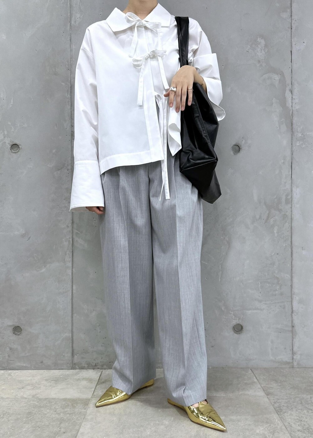 ゴールド系のパンプス、ホワイト系のシャツ/ブラウス、グレー系のスラックスを着用したレディースの秋コーディネートの2枚目の写真