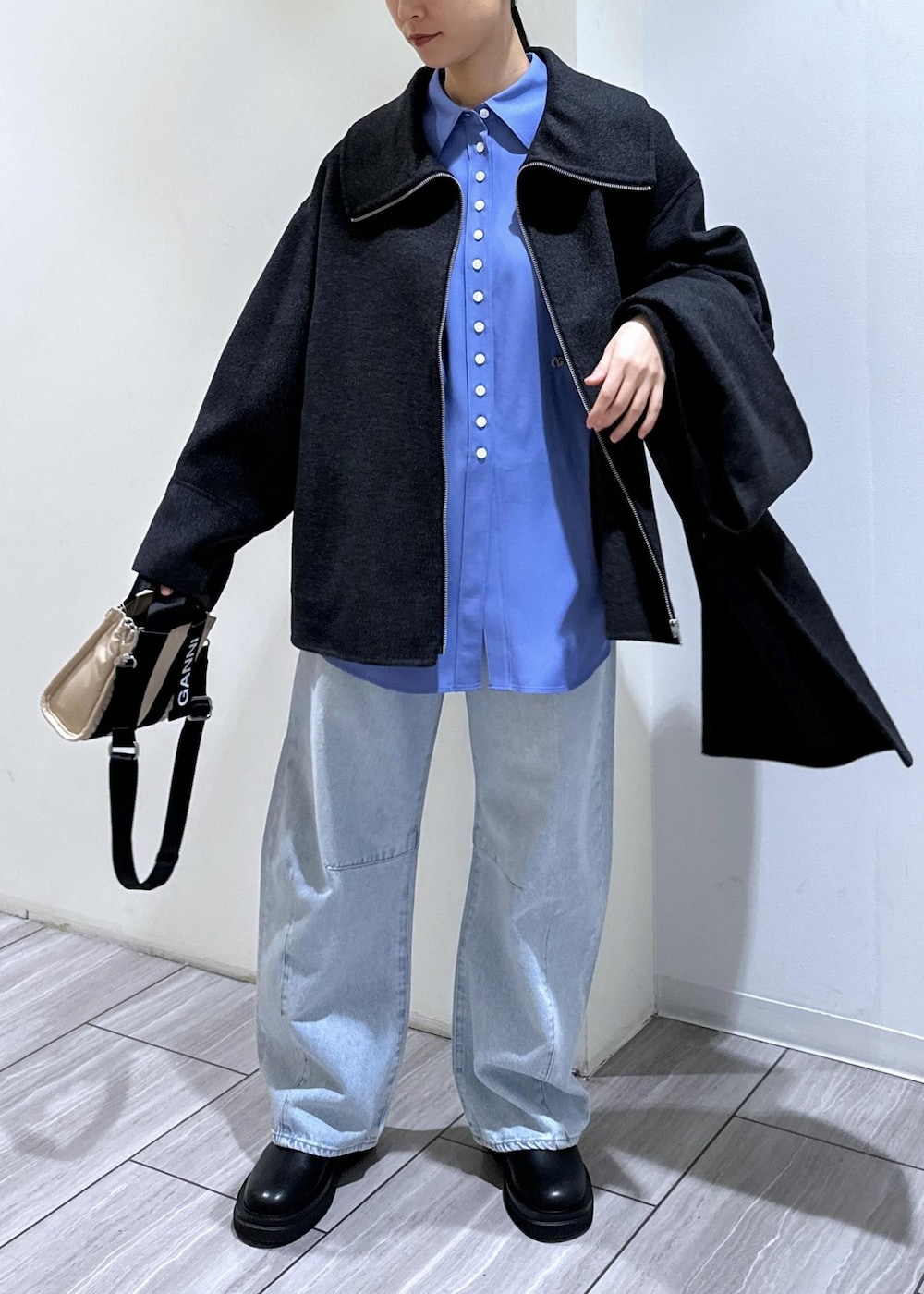 ブルー系のデニムパンツ、ベージュ系のトートバッグ、ブラック系のブーツを着用したレディースの秋コーディネートの2枚目の写真