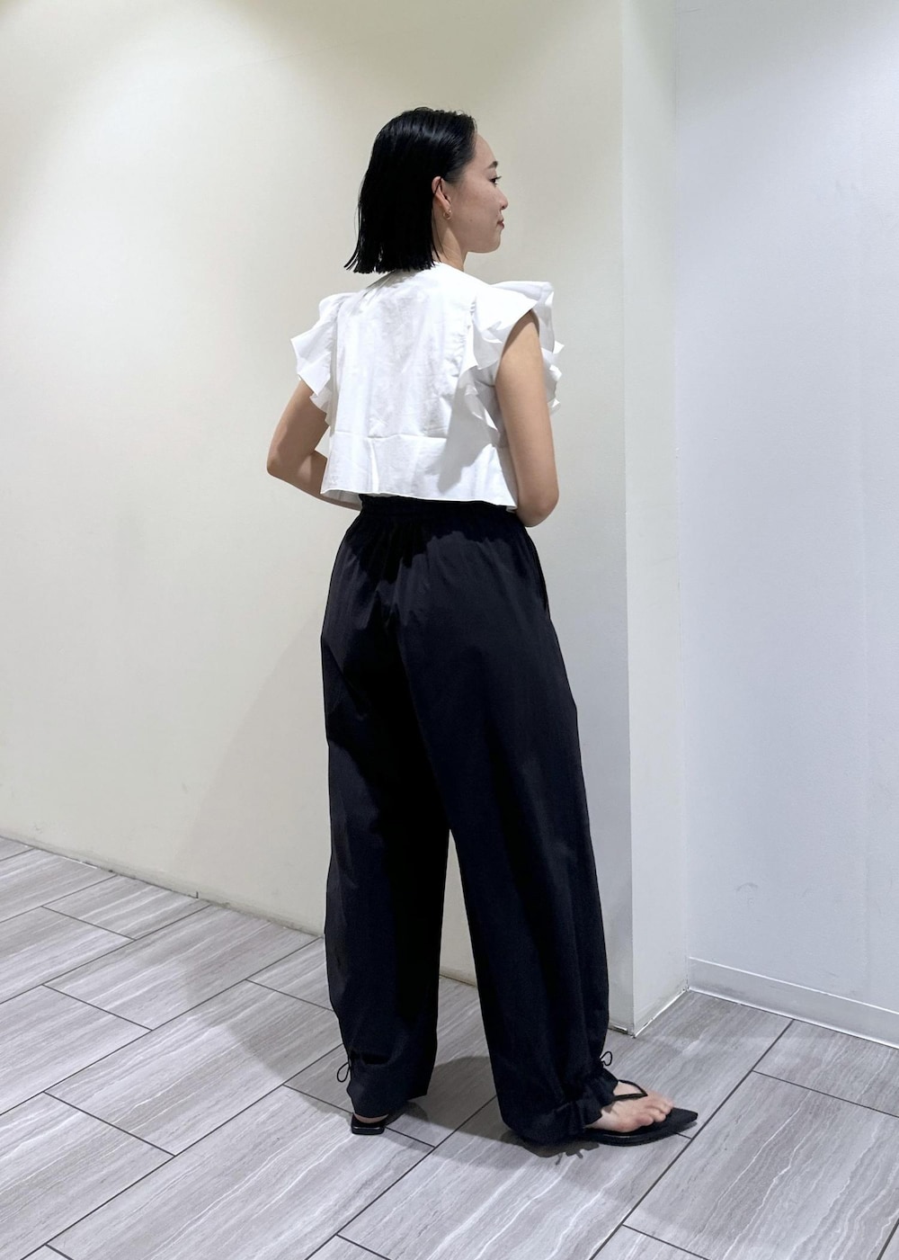ブラック系のサンダル、ホワイト系のTシャツ/カットソー、ブラック系のその他パンツを着用したレディースの夏コーディネートの6枚目の写真