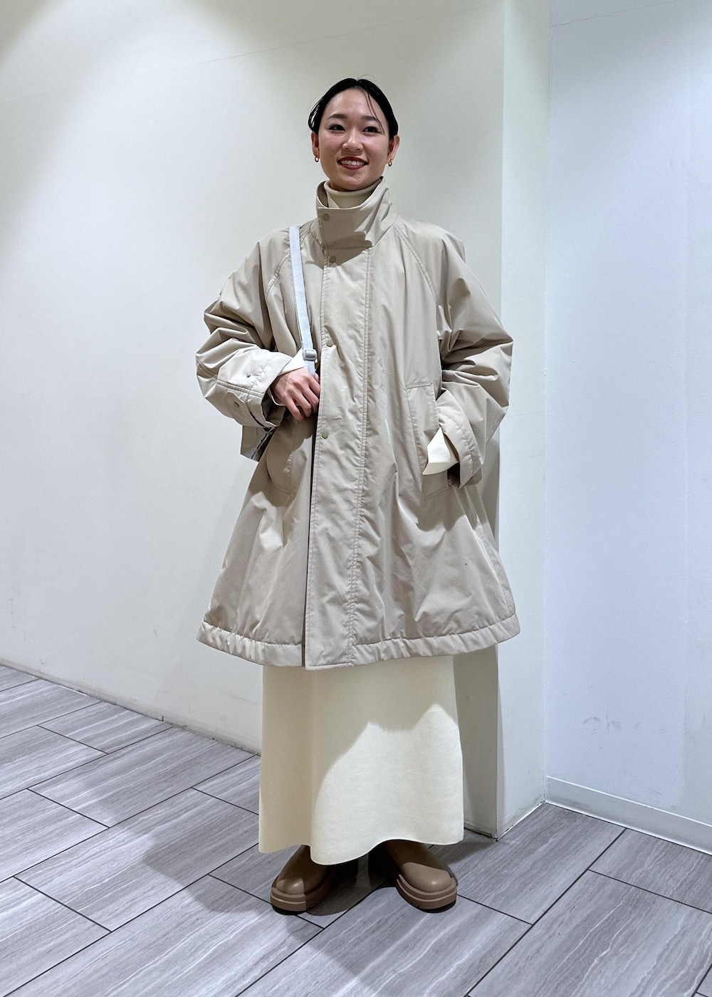 ベージュ系のブーツ、ホワイト系のワンピース、ベージュ系のその他アウターを着用したレディースの冬コーディネートの2枚目の写真