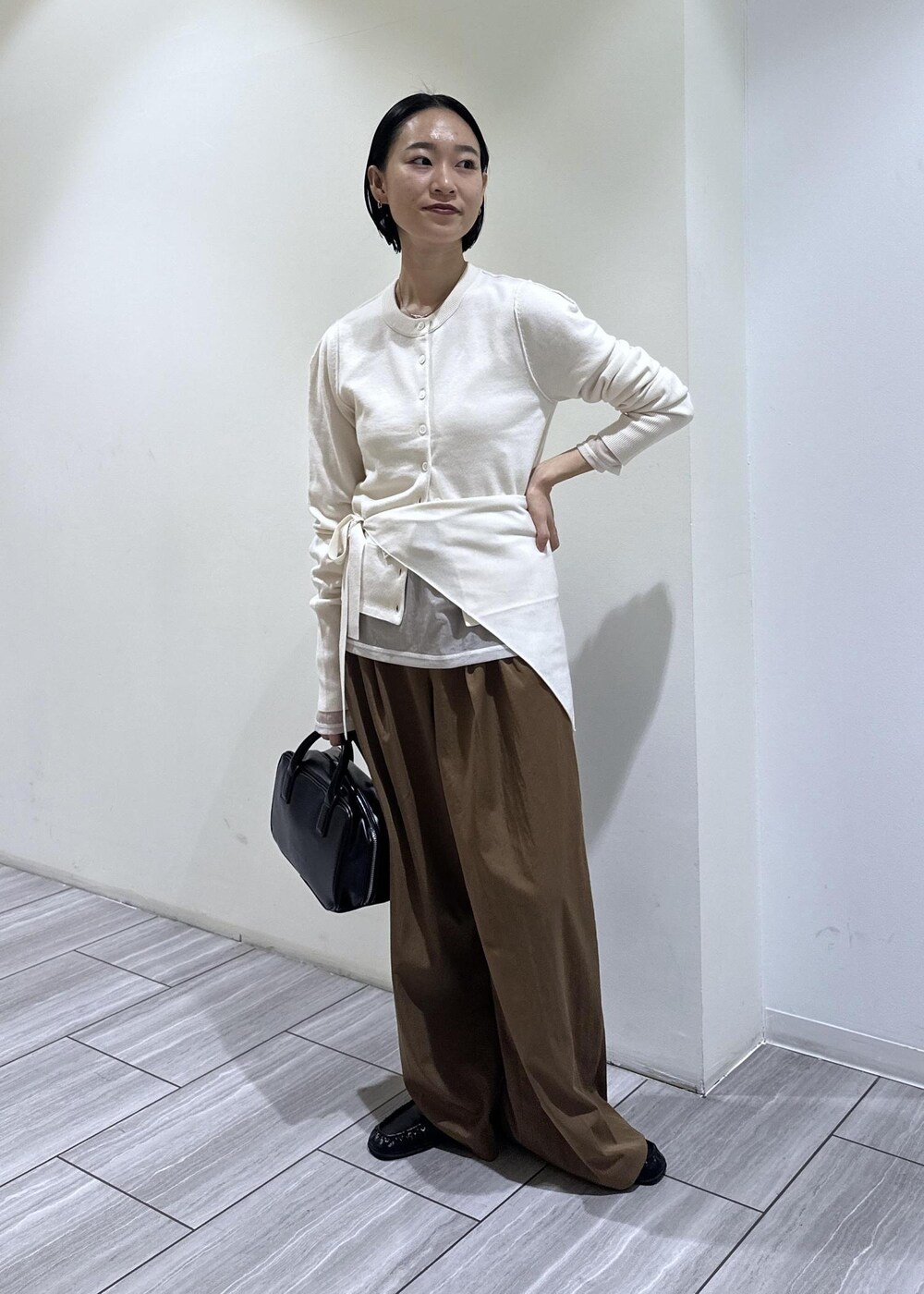 ブラック系のショルダーバッグ、ブラウン系のその他パンツ、ホワイト系のカーディガン/ボレロを着用したレディースの秋コーディネートの6枚目の写真