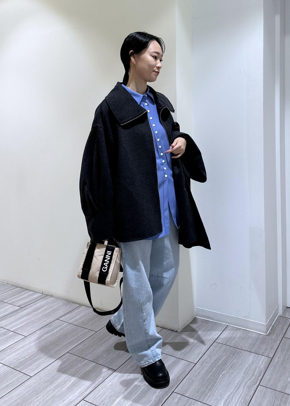 ブルー系のデニムパンツ、ベージュ系のトートバッグ、ブラック系のブーツを着用したレディースの秋コーディネートの6枚目の写真