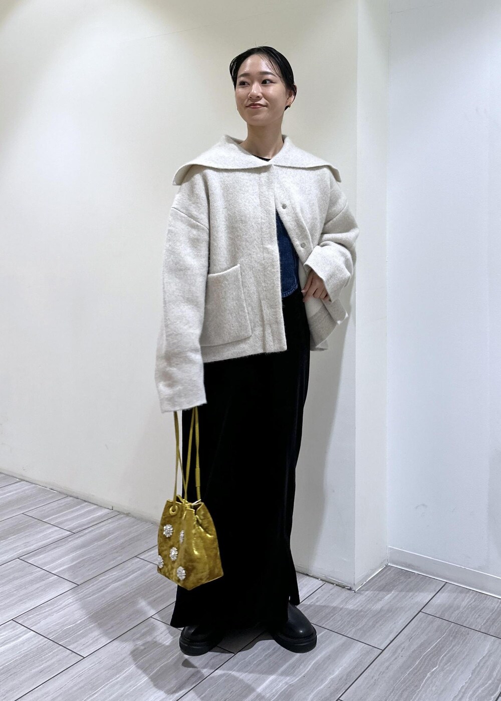 ブラック系のブーツ、ブラック系のワンピース、ホワイト系のカーディガン/ボレロを着用したレディースの秋コーディネートの2枚目の写真