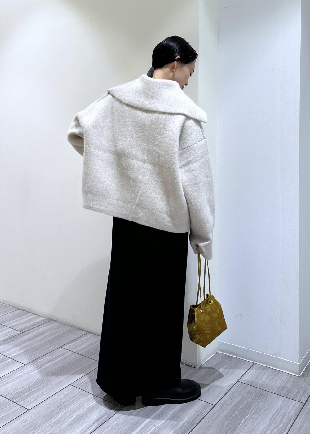 ブラック系のブーツ、ブラック系のワンピース、ホワイト系のカーディガン/ボレロを着用したレディースの秋コーディネートの4枚目の写真