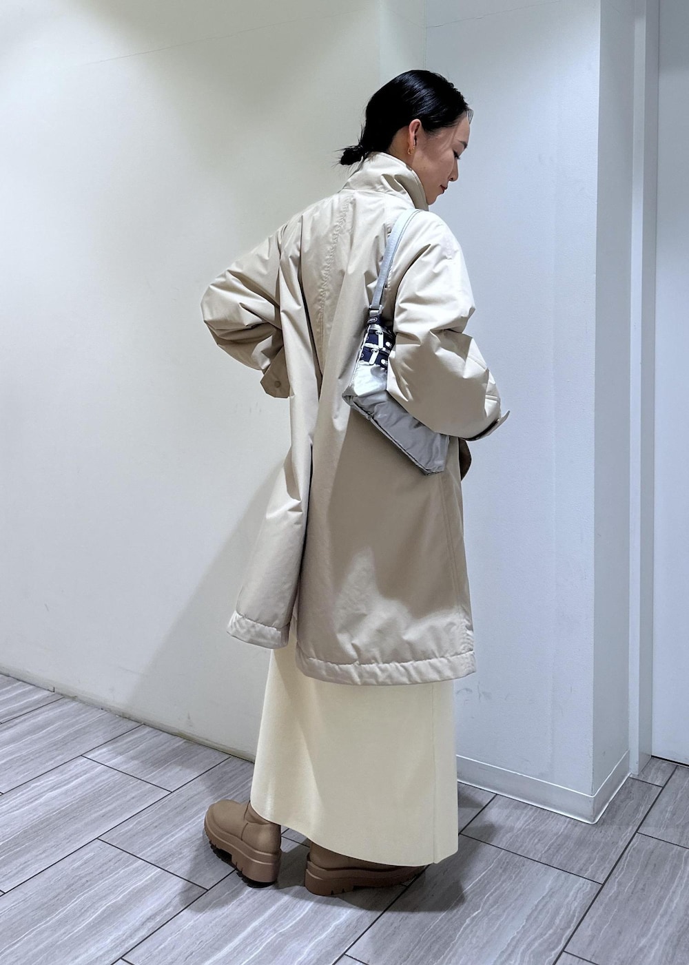 ベージュ系のブーツ、ホワイト系のワンピース、ベージュ系のその他アウターを着用したレディースの冬コーディネートの6枚目の写真