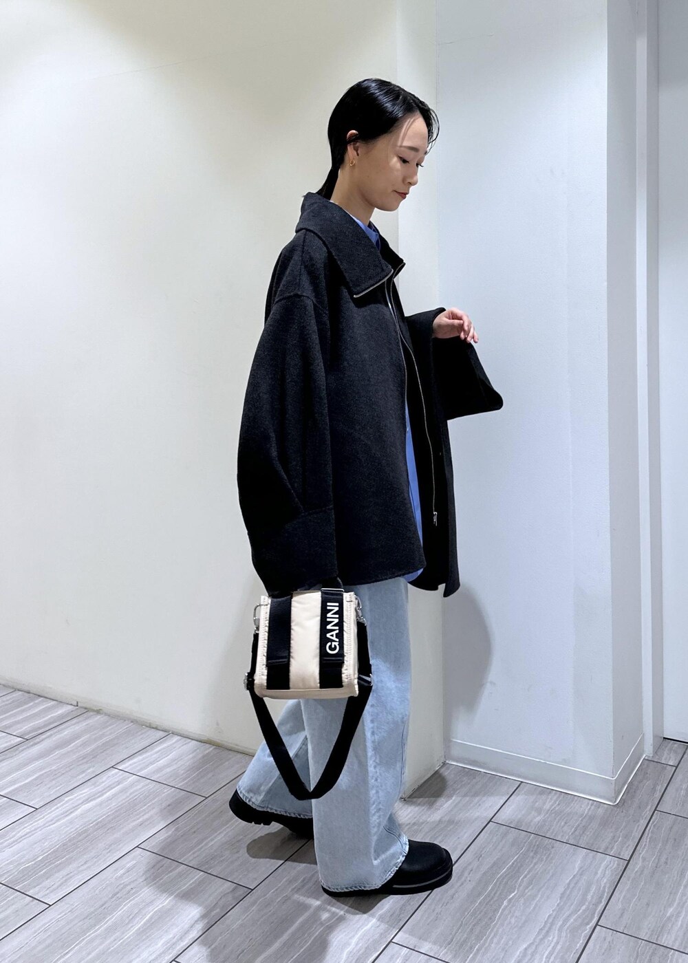 ブルー系のデニムパンツ、ベージュ系のトートバッグ、ブラック系のブーツを着用したレディースの秋コーディネートの5枚目の写真