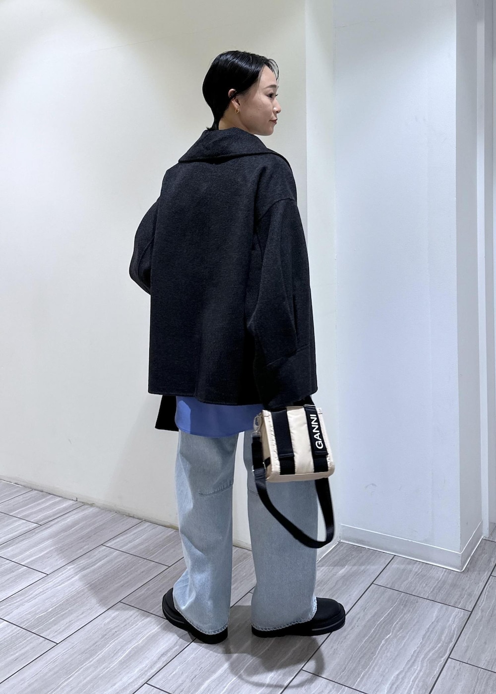 ブルー系のデニムパンツ、ベージュ系のトートバッグ、ブラック系のブーツを着用したレディースの秋コーディネートの4枚目の写真