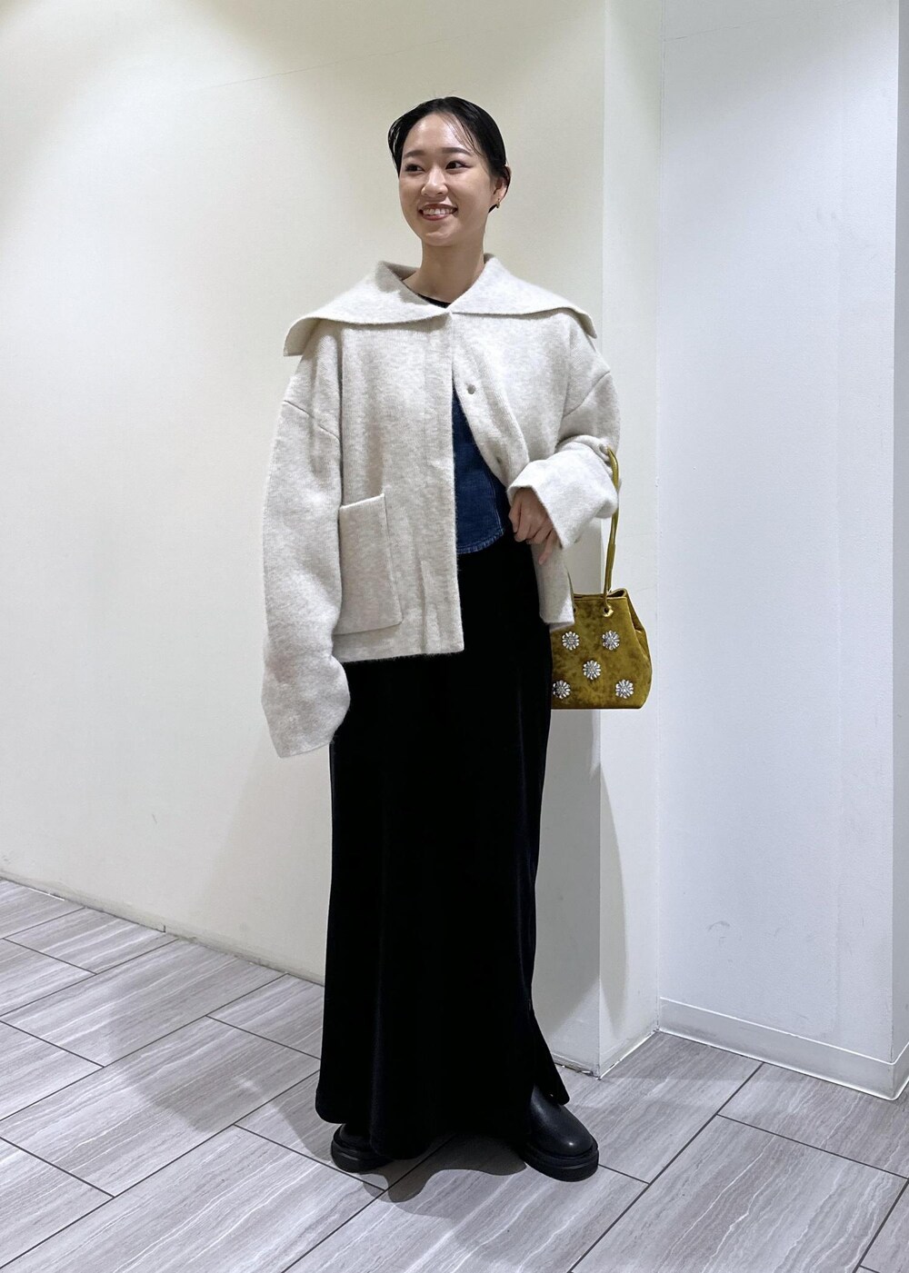 ブラック系のブーツ、ブラック系のワンピース、ホワイト系のカーディガン/ボレロを着用したレディースの秋コーディネートの6枚目の写真