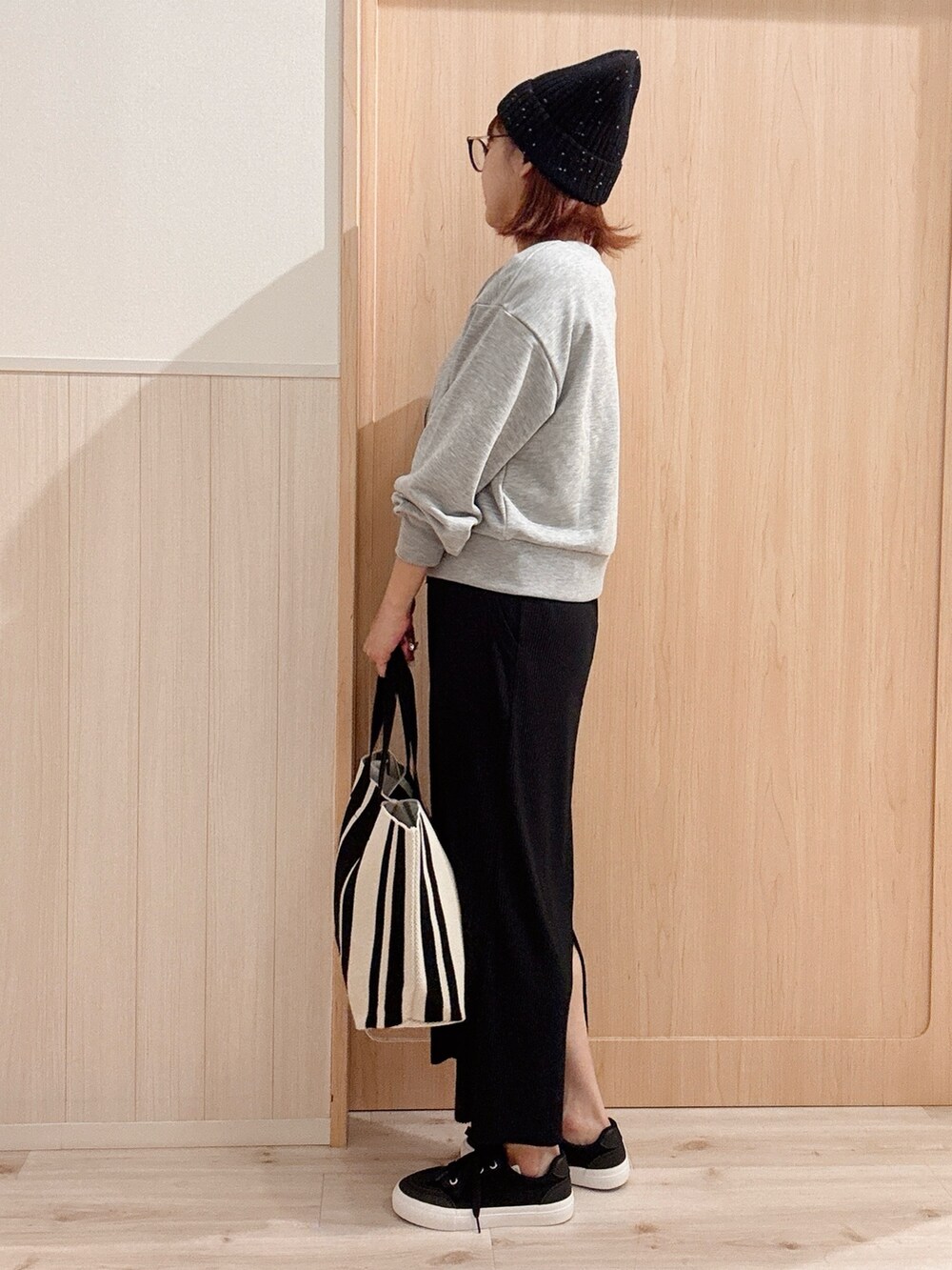 ブラック系のスニーカー、ブラック系のスカート、ブラウン系のトートバッグを着用したレディースの秋コーディネートの2枚目の写真