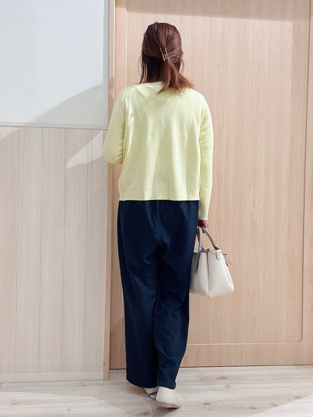 イエロー系のニット/セーター、イエロー系のカーディガン/ボレロ、ベージュ系のトートバッグを着用したレディースの春コーディネートの3枚目の写真