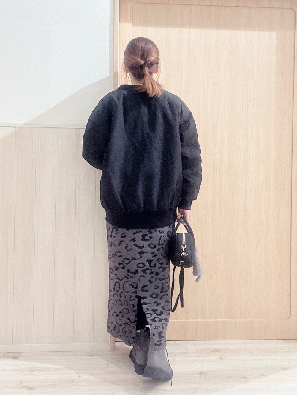 ブラウン系のブーツ、ブラック系のボストンバッグ、グレー系のスカートを着用したレディースの冬コーディネートの3枚目の写真